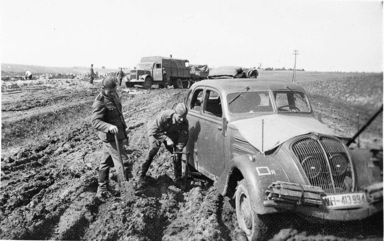Оберефрейтор и рядовой используют домкрат для извлечения из дорожной колеи трофейного французского а