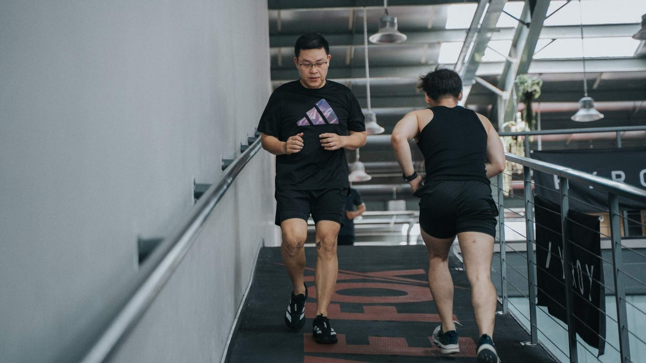 Hai người chạy bộ trên dốc trong khu vực cardio tại Active Fox, một phần của chương trình Hybrid Training