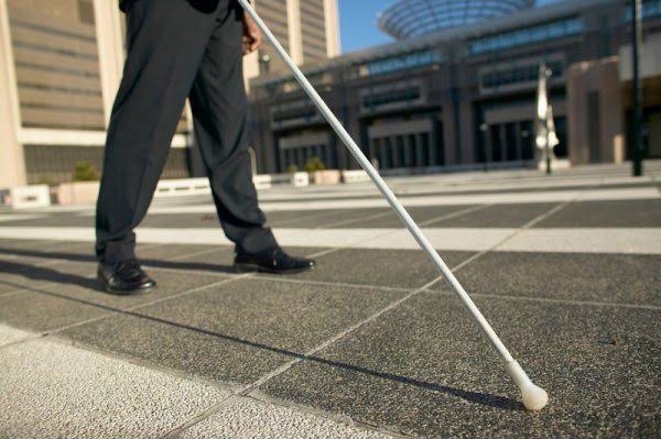 Blind African man walking confidently with white cane
