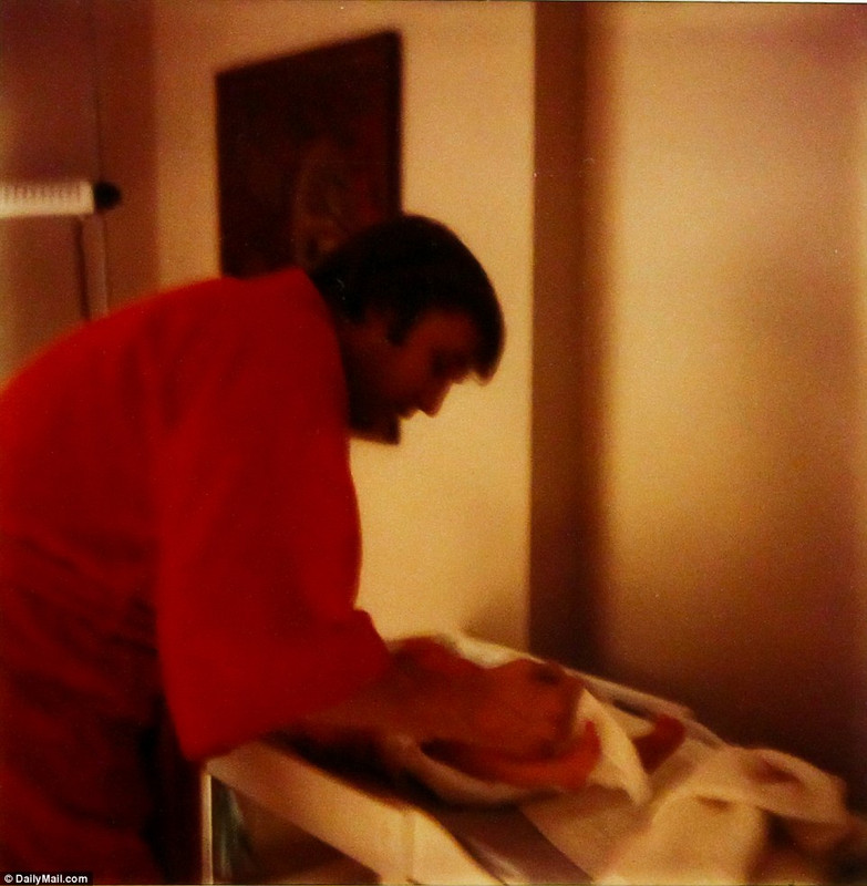 Donald Trump changing the diaper of his son in a red gown.