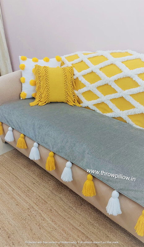 Grey and yellow diamond patterned sofa cover with white and yellow tassels