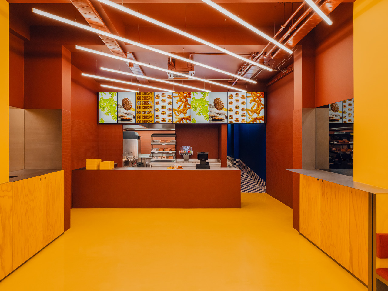 Theken- und Gastronomiebeleuchtung bei Flip-N-Fry mit starken Farbflächen und linearen Deckenleuchten