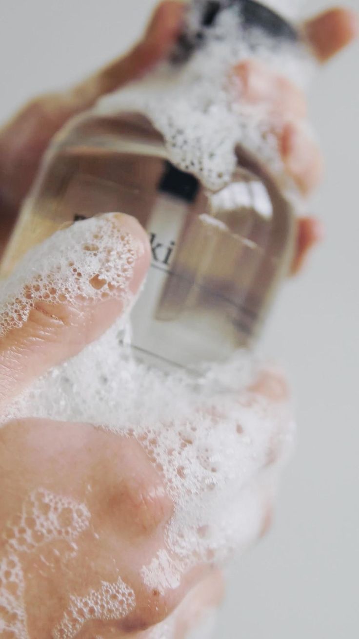 Female hands in foam hold a bottle of shampoo