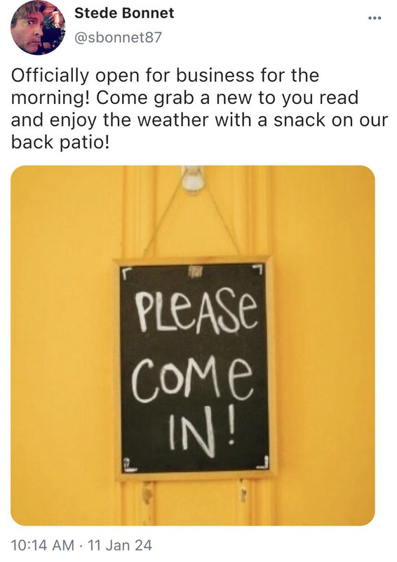 @sbonnet87 Officially open for business for the morning! Come grab a new to you read and enjoy the weather with a snack on our back patio! *photo of a yellow door with a sign that reads Please Come In!*