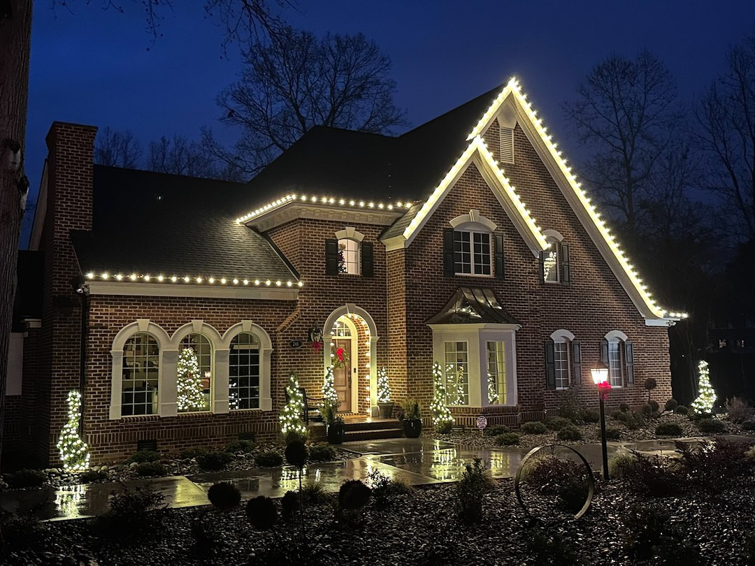 A Merry Crew holiday light installation on a home at night
