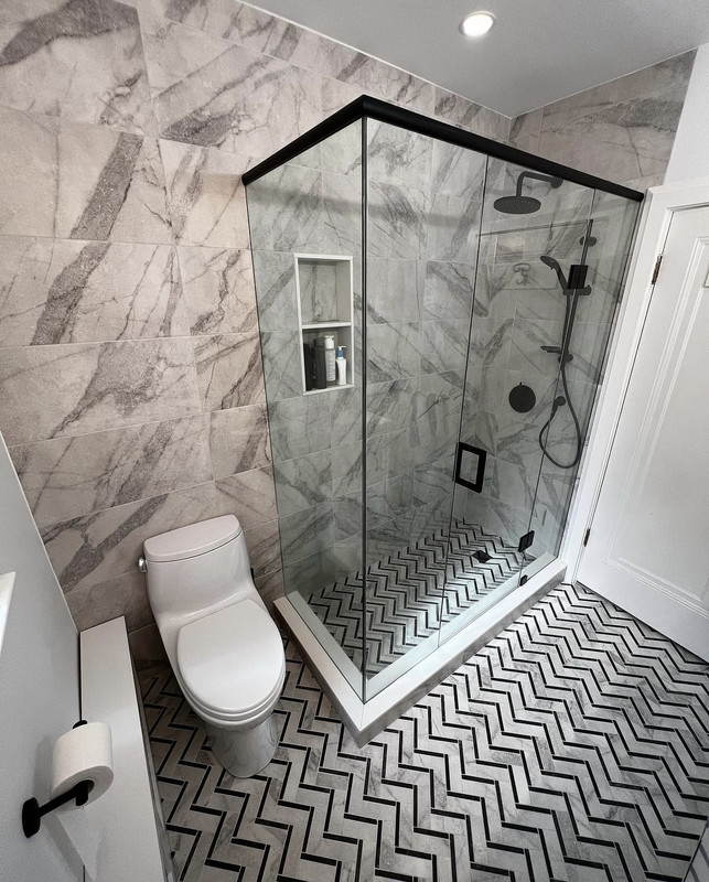 After — second angle of shower showing marble-look tile, niche, matte black rain head