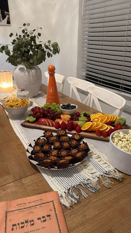A Shabbat table spread with fruit, snacks, and dessert