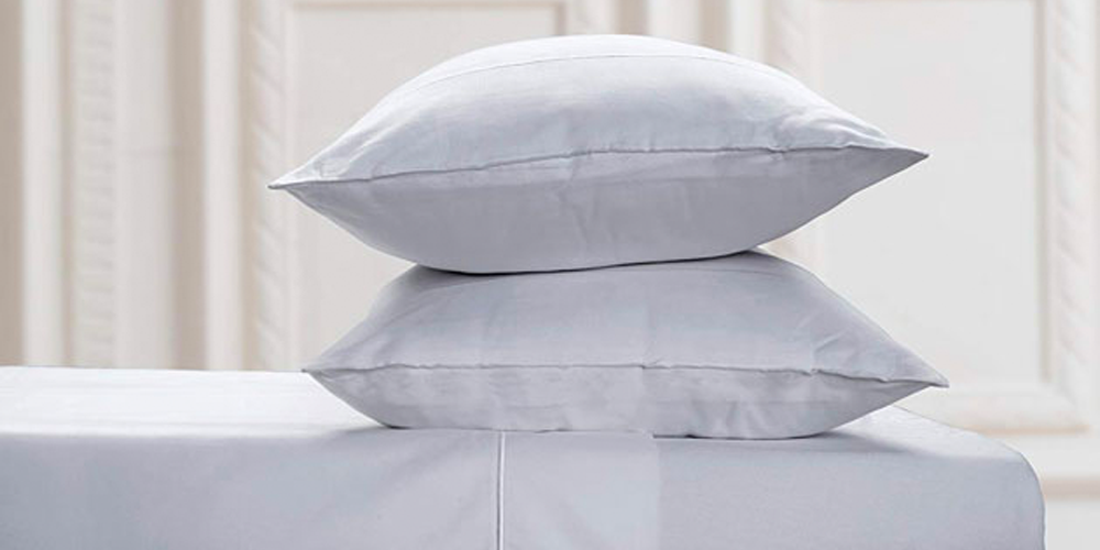 A white bed with a stack of two white pillows