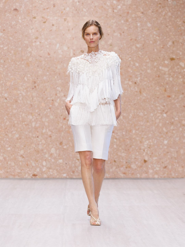 Chloé SS27, Eva Herzigova torna in passerella Eva Herzigova sfila per Chloé SS27 con top bianco a frange e bermuda coordinati