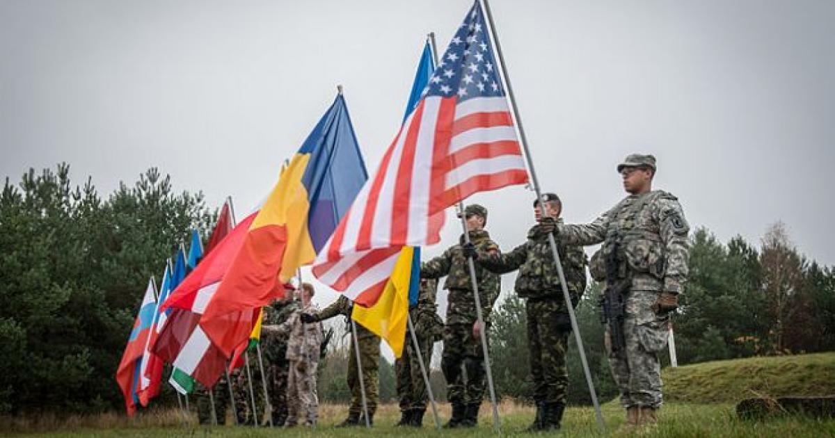 Valami magyar cikkíró eldicsekedett azzal, hogy nekünk milyen gazdag harci tapasztalataink vannak a NATO-val. Azért az ukránok sem ültek ölbe tett kézzel az évek során. Nagyon sok NATO hadgyakorlaton vesznek részt, a Lvov megyei (Galícia) Jaroviv lőtér gyakorlatilag a NATO rendelkezésére áll. Egész évben, zászlóaljak váltásával folyik az ukrán katonák ki-, illetve továbbképzése. Nagy amerikai haditengerészeti támaszpont-komplexum épül a Fekete-tenger északnyugati szögletében, az Ogyesszától északkeletre fekvő OCSAKOV várossal a központban, a Krím hátában, attól mindössze 150 km-re. Évről évre Ogyessza mellett zajlik a NATO "Sea Breeze" nevű hadgyakorlata, természetesen ukrán részvétellel. Gyakorlatilag folyamatos, szabad bejárást kaptak Ukrajna területére, korlátlanul, egész évre, évenkénti formális meghosszabbításokkal. Beregszászra (a határunktól 10 km-re) egy felderítő-diverzáns zászlóaljat telepítenek, amelynek rendszeres továbbképzését brit kiképzők végzik majd. A képen elölről a második az ukrán zászló - az amerikai és román zászló között, az amerikai takarásában.