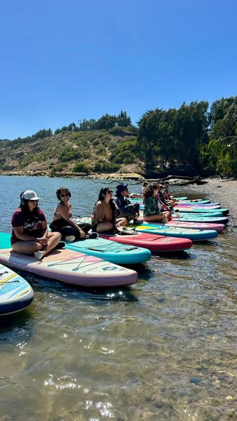 Participantes sentados en sus tablas de SUP a la orilla del río Rapel