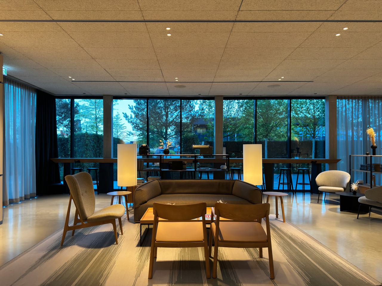 Modern hospitality lighting in the Coreum Hotel lounge with warm pools of light, exposed concrete and natural materials