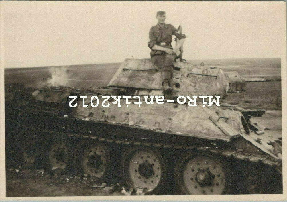 Soldat posiert auf zerstörten T-34 Panzer der Russen