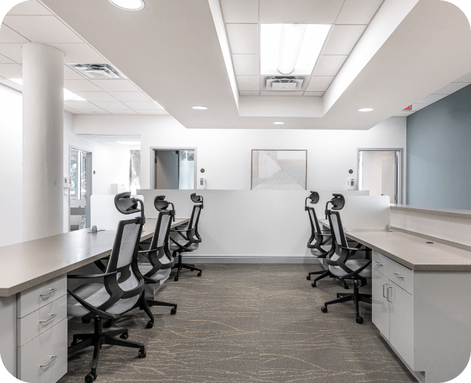 A well-organized workspace with multiple ergonomic chairs and desks, suitable for collaborative work or individual tasks. The room is brightly lit with a minimalist design.