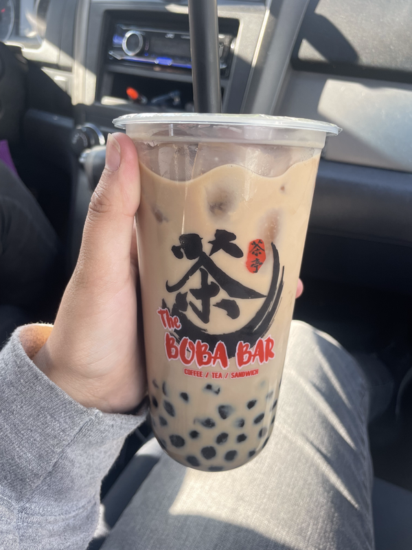 a photo of a rounded but tall cup of boba in my hand. i got a house tea, so it's light brown!