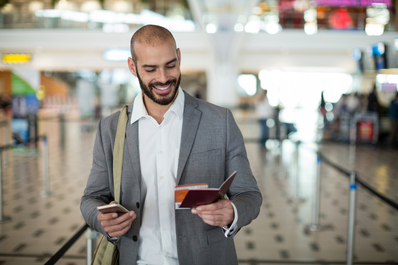 [Image: smiling-businessman-holding-boarding-pas...-phone.jpg]