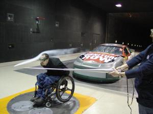 Josh Winkler in wheelchair in wind tunnel with smoke blowing over him