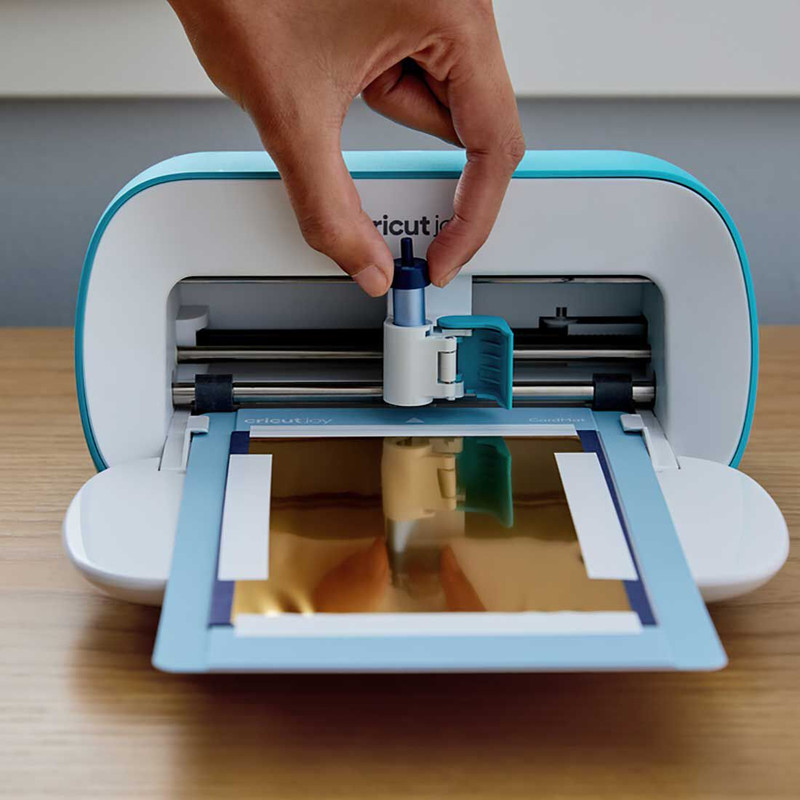 Una persona colocando la herramienta de foil en la máquina de corte Cricut Joy.