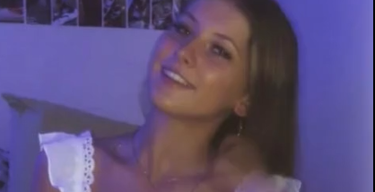 A Girl Standing In A White Short Dress, Showing Off Her Boobs.