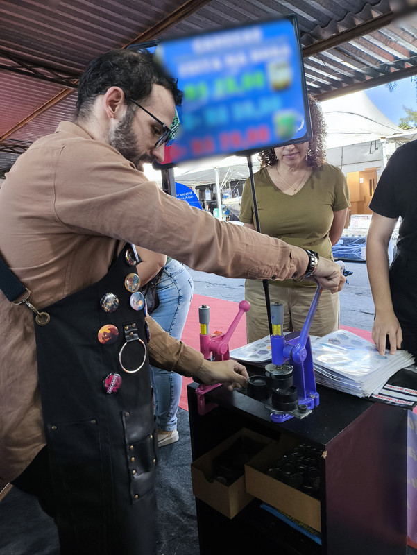 Henrique fazendo bottons com cliente na feira