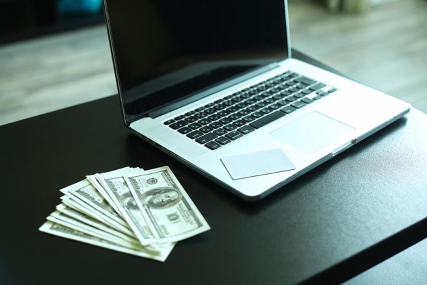 Workplace with money and notebookus dollar banknotes near laptop Workplace with money and notebookus dollar banknotes near laptop