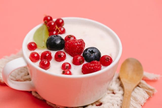 Bowl of plain yogurt topped with fresh berries, providing probiotics and nutrients that support a healthy gut microbiome.