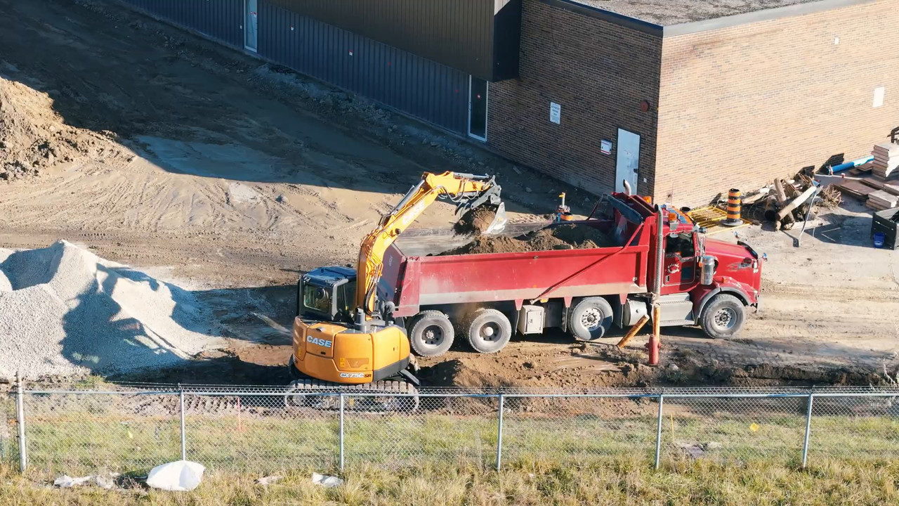 Excavator loading a dump truck beside the TWI Foods plant