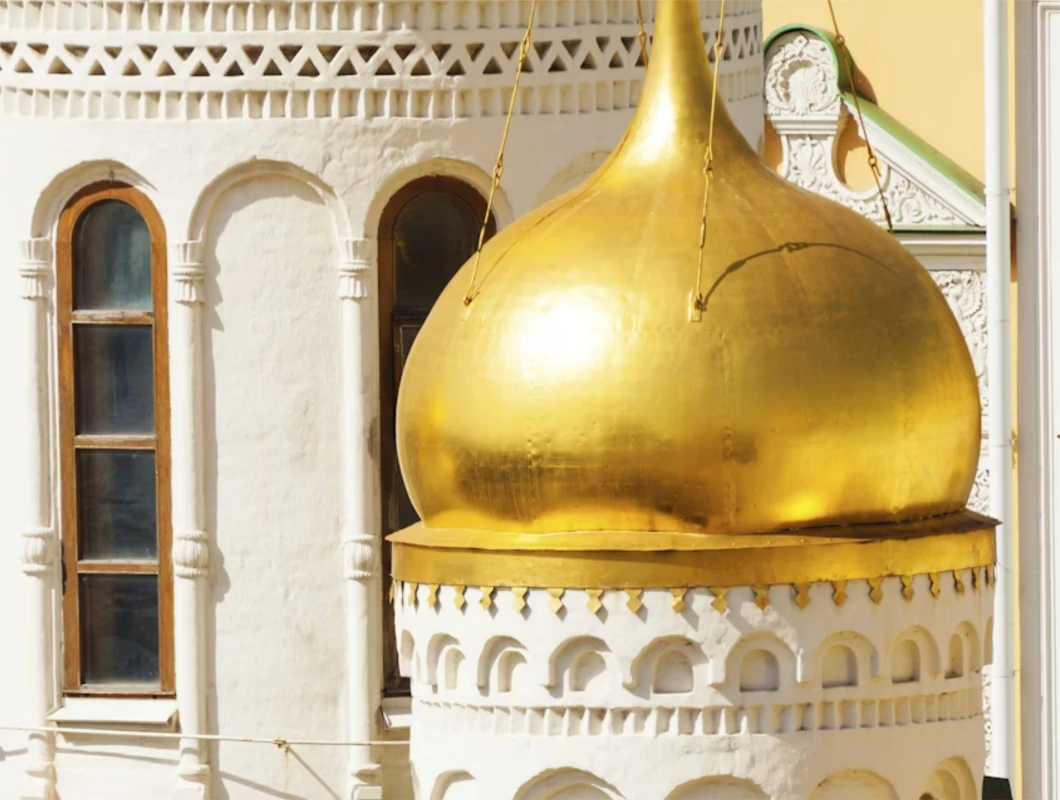 Close-up view of golden onion domes and white drum of a Kremlin cathedral