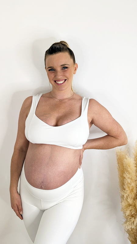 Femme enceinte en tenue de sport blanche.