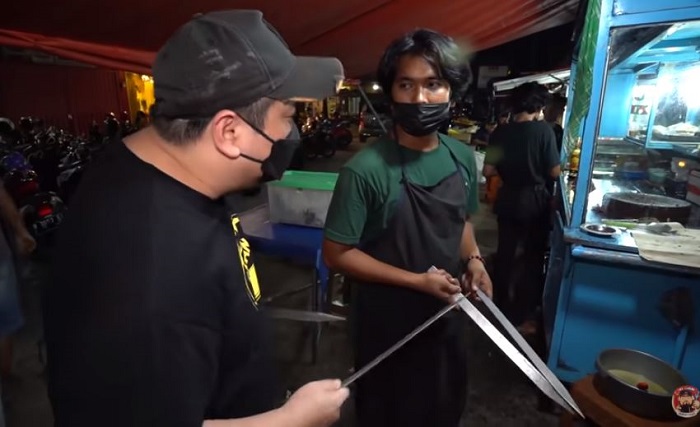 Arjun saat menunjukkan aluminium berbentuk seperti pedang yang digunakan sebagai alat untuk membakar ayam.