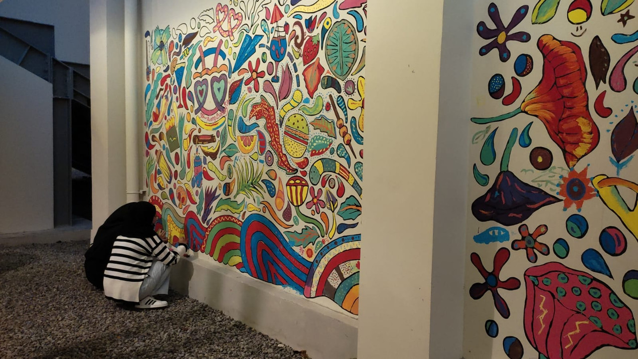 Pengunjung sedang mewarnai mural di Pameran Tak Kenal Maka Tak Sayang yang diadakan di Lokananta Bloc Solo pada 14 Juli hingga 31 Agustus 2023.