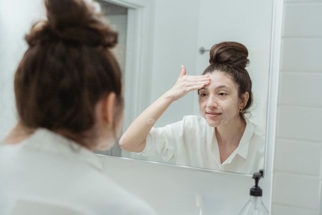 a woman cleansing her face with gentle cleanser to heal her skin barrier 
