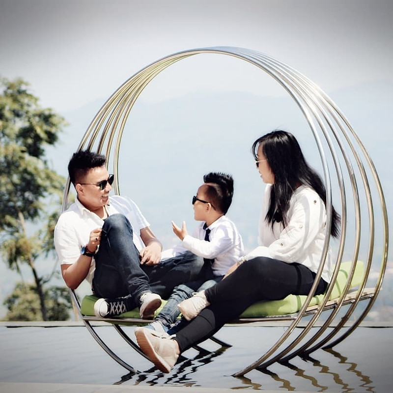 Pengunjung bersama keluarga tengah menikmati area spot foto berlatarbelakang pegunungan