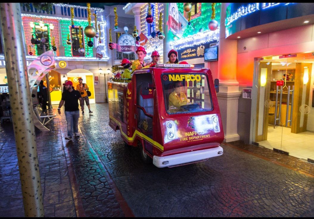 A man pushing a stroller inside Kidzania Dubai, surrounded by playful activities