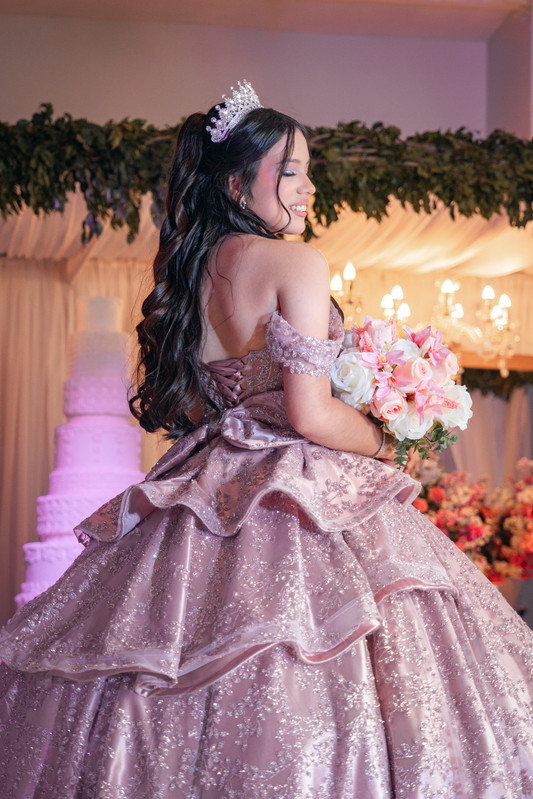 Quinceañera con su ramo bajo el candelabro de la celebración