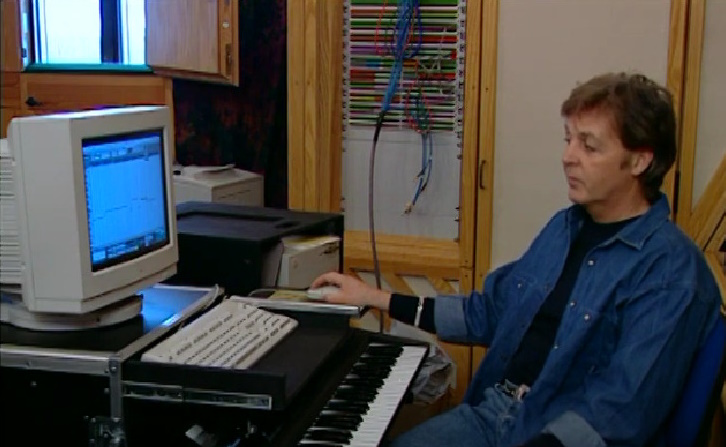 Paul McCartney sitting at an 1990s style computer.