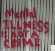 cropped image of red spray paint on Mike Kelly’s office window reading Mental Illness is not a crime in red spray paint the window is a simple large clear panel and all that lies behind the text are boring off white vertical blinds
