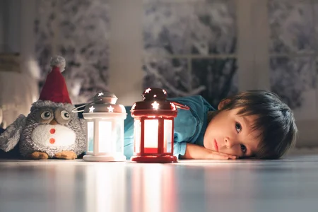 49968341-beautiful-little-boy-lying-down-on-the-floor-looking-at-candles-making-wishes-for-christmas.webp