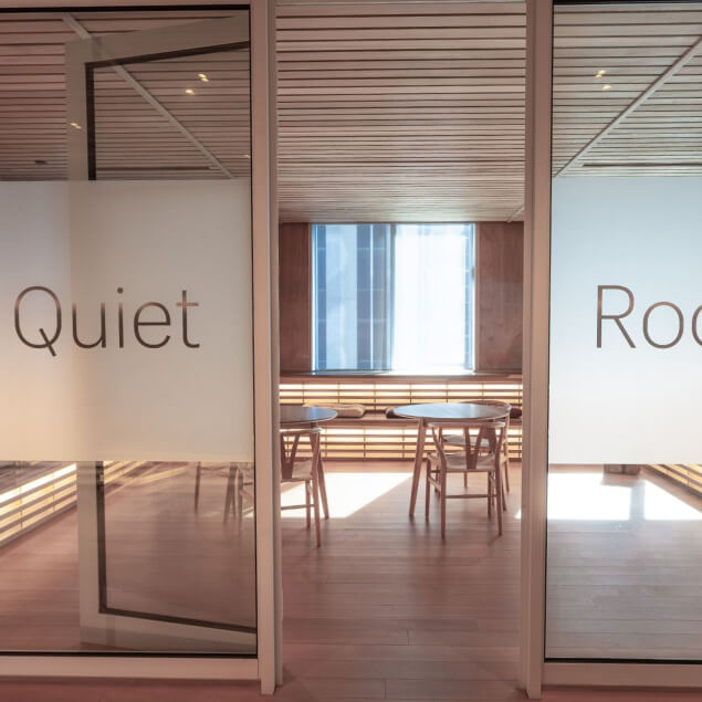 Outside of a quiet room, with frosted glass windows and tiered benches visible.