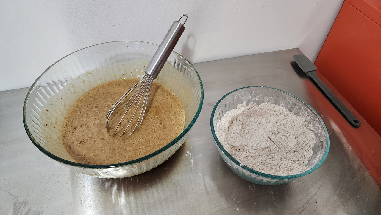 The ingredients for the banana bread, mixed within two bowls. The wet ingredients are in the left bowl, and the dry ingredients are in the right bowl.