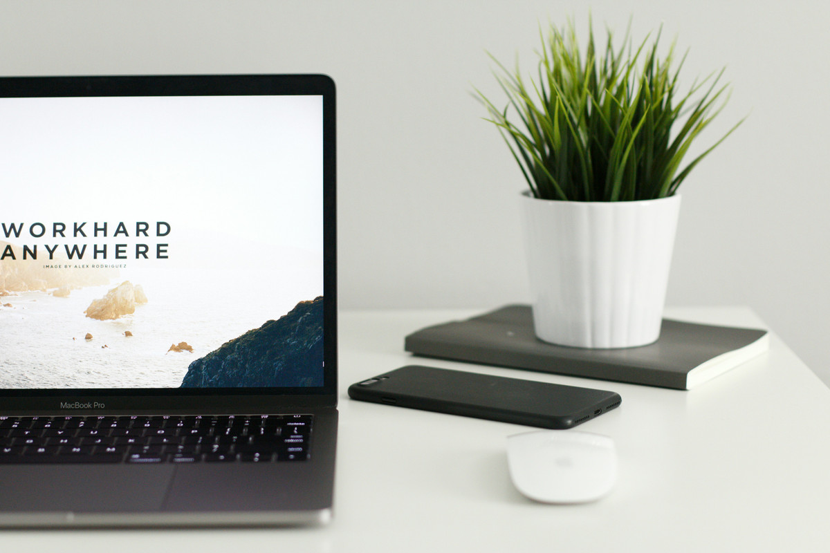 Laptop with motivational quote and a potted plant on a book