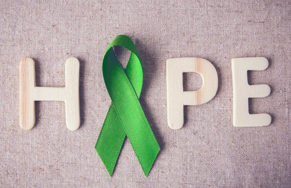 The word hope and a green ribbon representing mental health awareness month. 