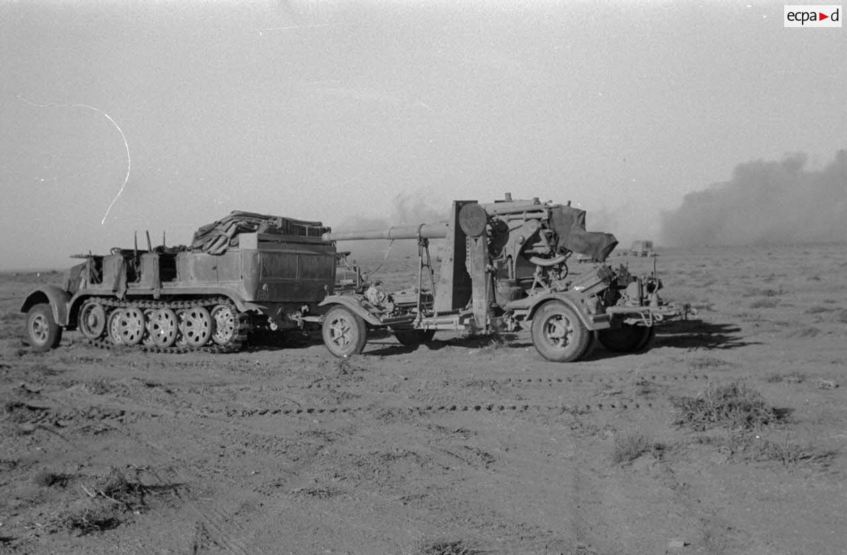 Un semi-chenillé Sd.kfz.7 tractant un canon de 8,8 cm Flak durant un tir d'arillerie britannique.