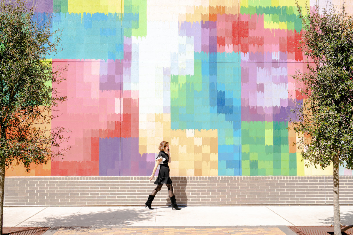 A woman walking down a sidewalk with a suitcase