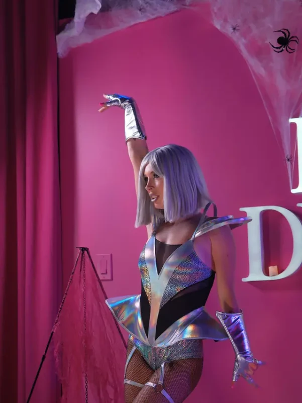 A guest in a silver costume dancing under the spiderweb decor