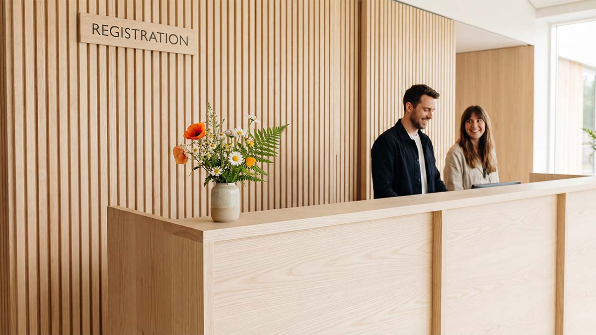 Лаконичная стойка регистрации из светлого дерева с живыми цветами