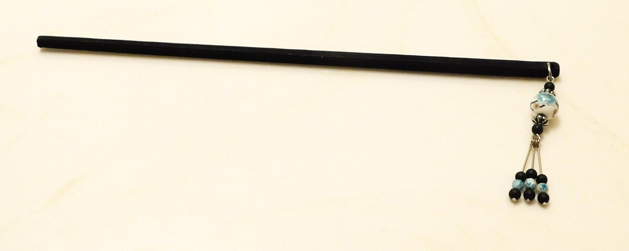 A wooden hair stick ornamented with beads of ceramic and stone.