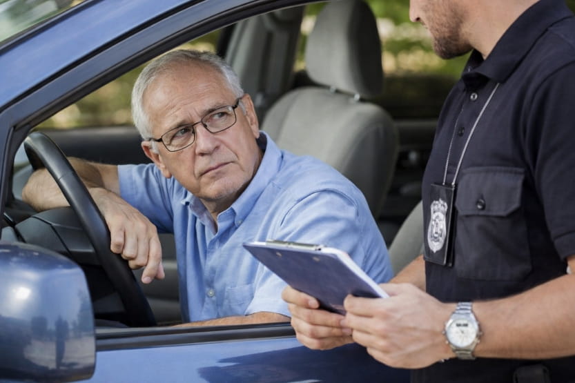 police officer reviewing documents with an older driver during a roadside stop