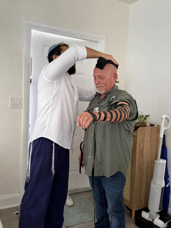 Community members helping each other put on tefillin