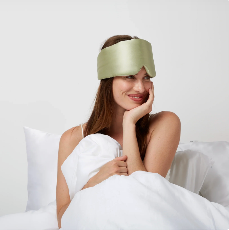 Woman wearing silk sleep mask in bed
